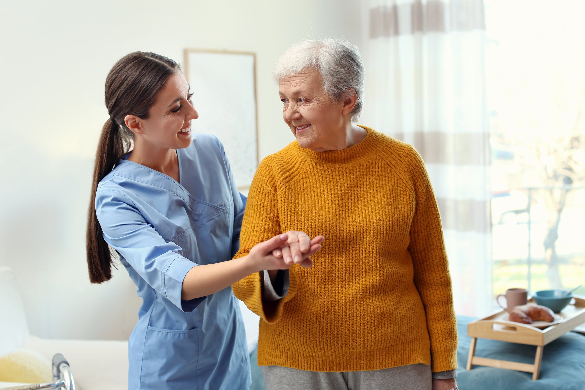 Care Worker Helping Elderly Woman to Walk in Geriatric Hospice